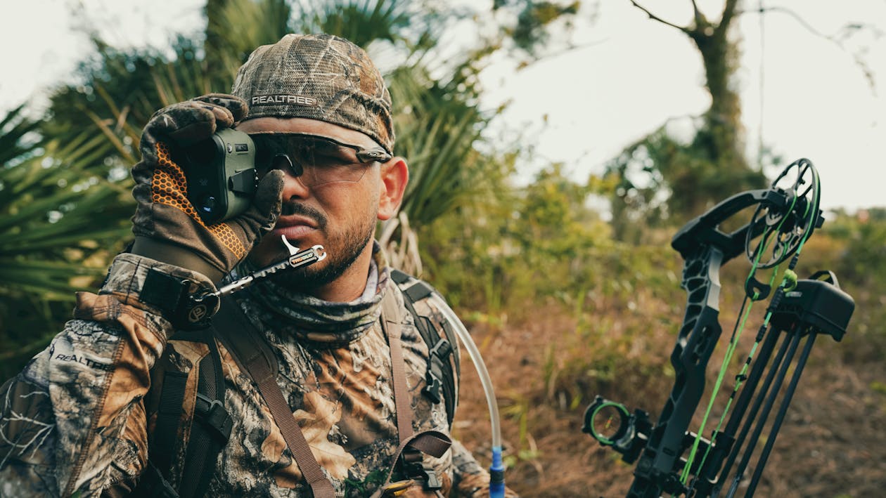 Eight hunting rangefinders lined up on a rock ledge overlooking a Western mountain valley at golden hour