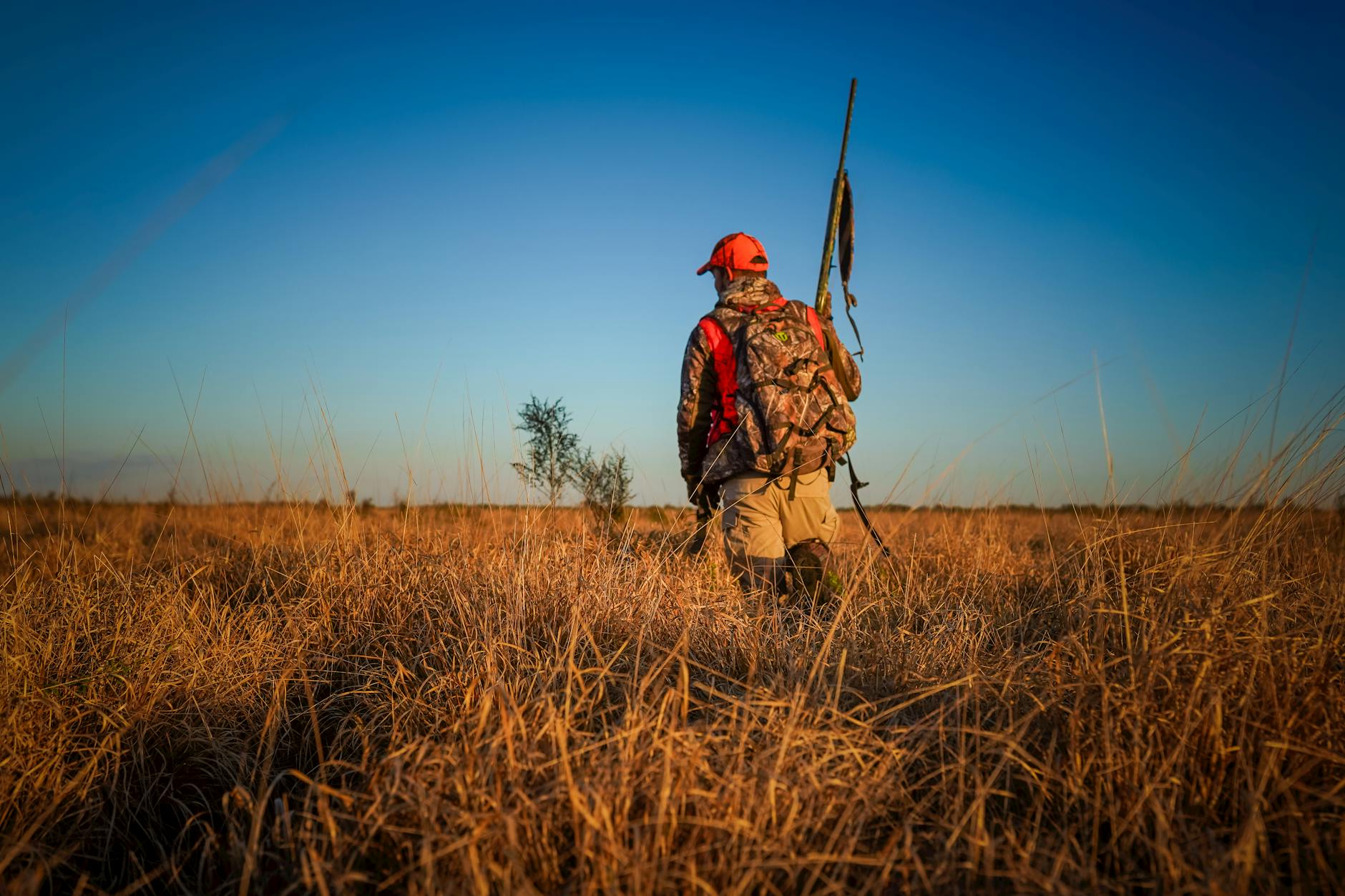 Charts comparing elk harvest success rates across hunting units with a hunter reviewing the data on a tablet