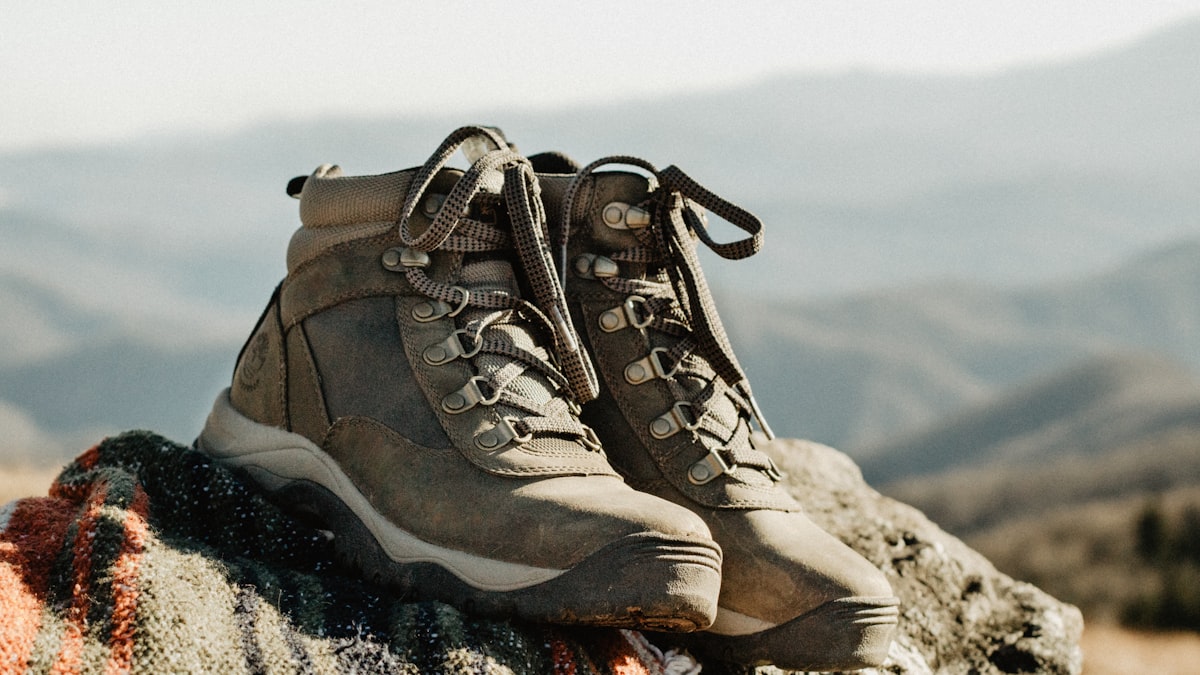 Pair of leather mountain hunting boots on a rocky alpine ridge with fall hunting terrain in the background