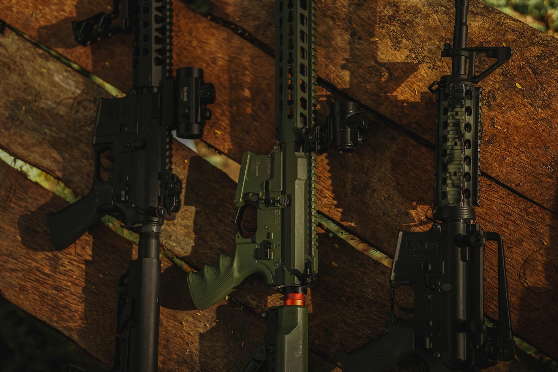 Three bolt-action hunting rifles laid side by side on a workbench with ammunition and scopes